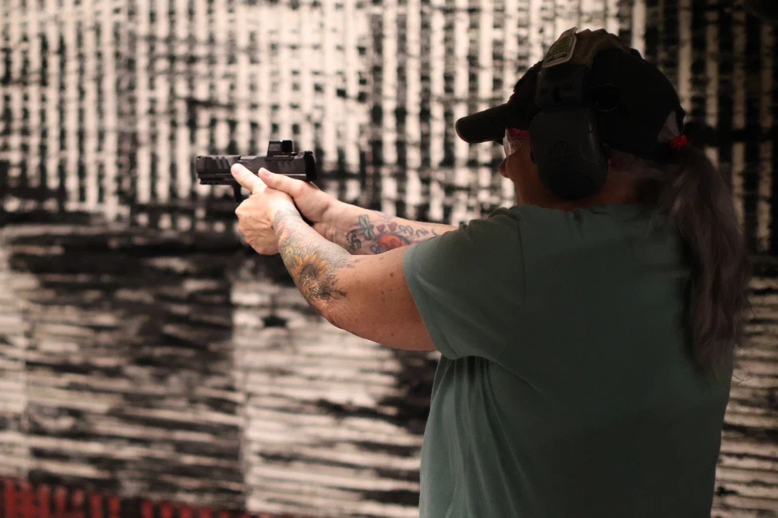 A shooter aiming a pistol that has a red-dot sight