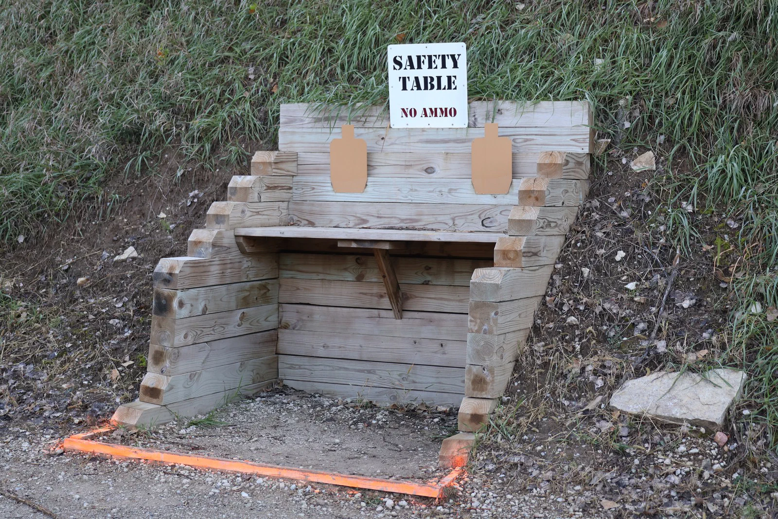 A wooden Safety Table built into a hillside, with an orange line marking the area on the ground