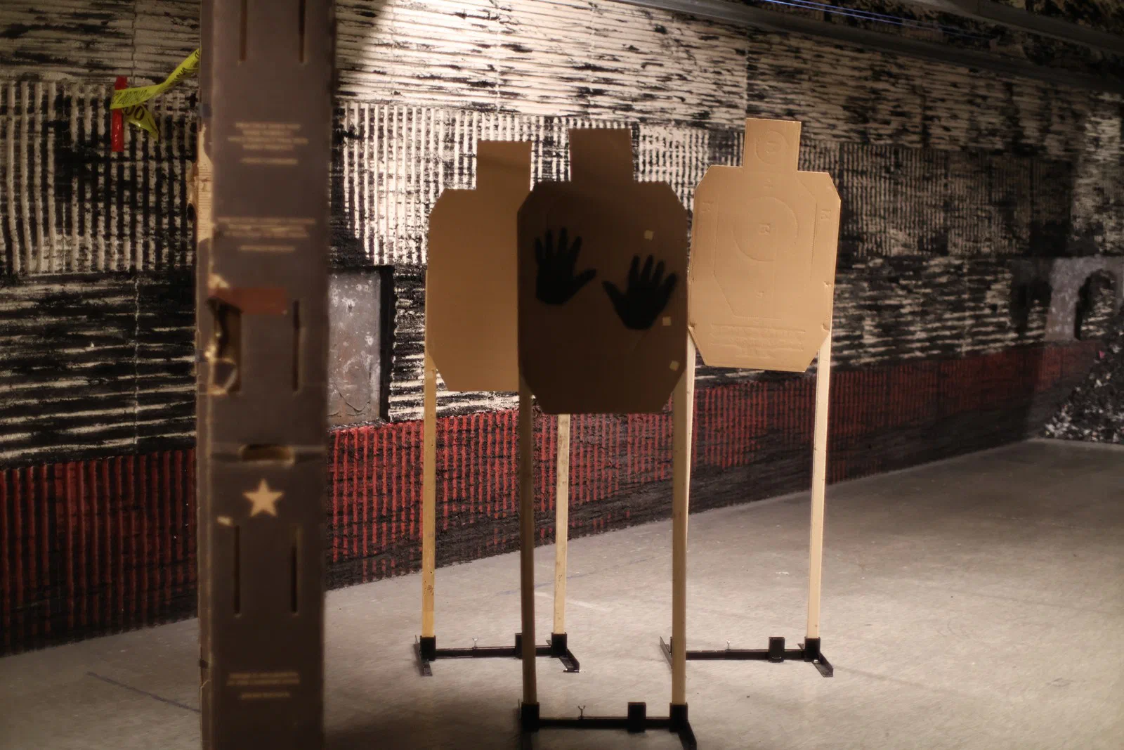 Cardboard targets on stands beside a wall prop, two marked with open hands