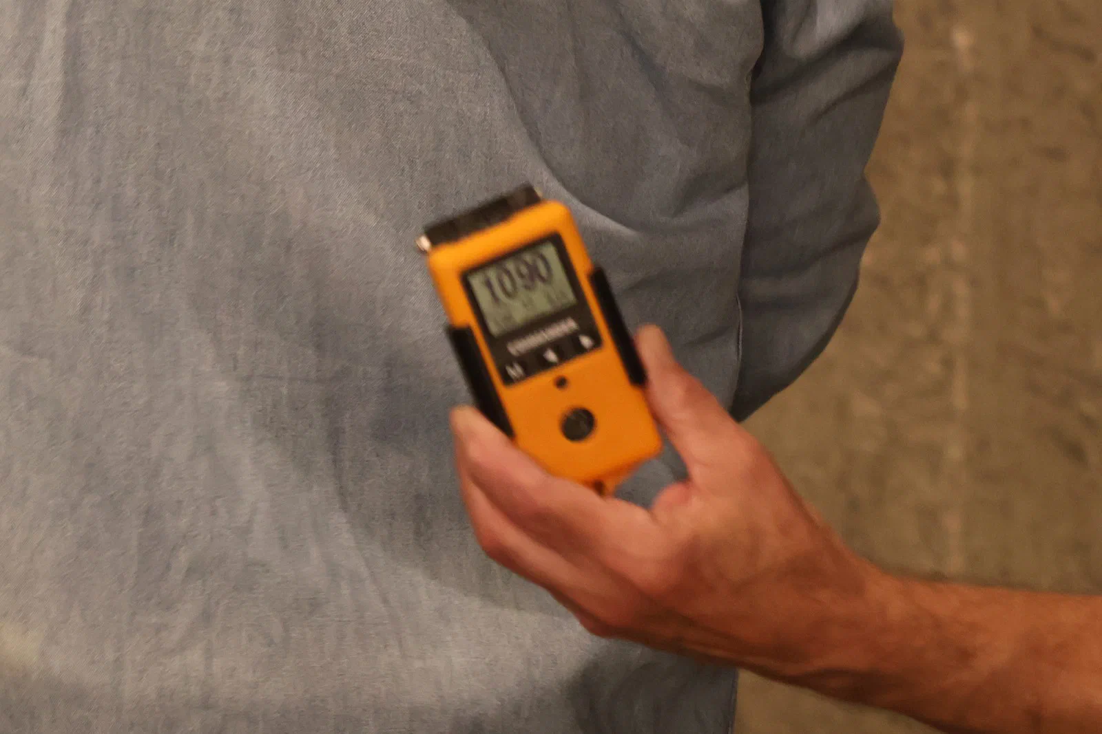 A hand holding an orange shot timer that reads 10.90